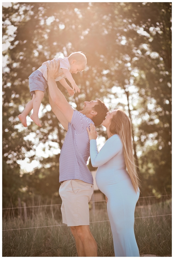 Pregnant mother and her young son walking hand in hand along the beach during a sunset maternity session photographed by a Baltimore Newborn Photographer.